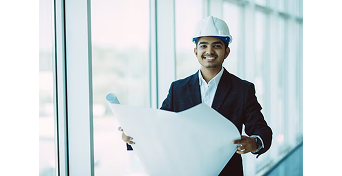 Principal employer holding site plans by a window